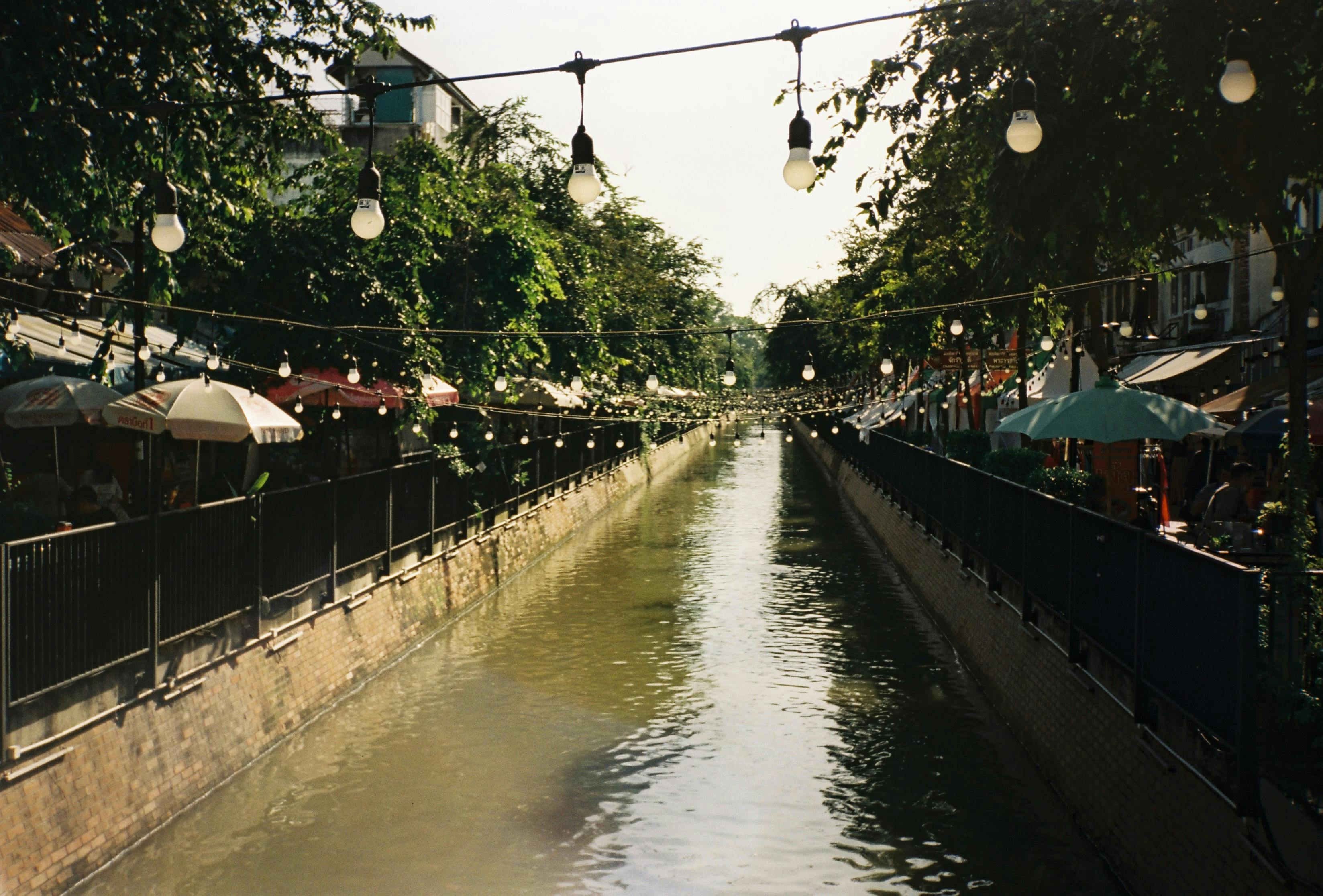 Charming canal with hanging lights and vibrant umbrellas in Bangkok, perfect for urban explorations.