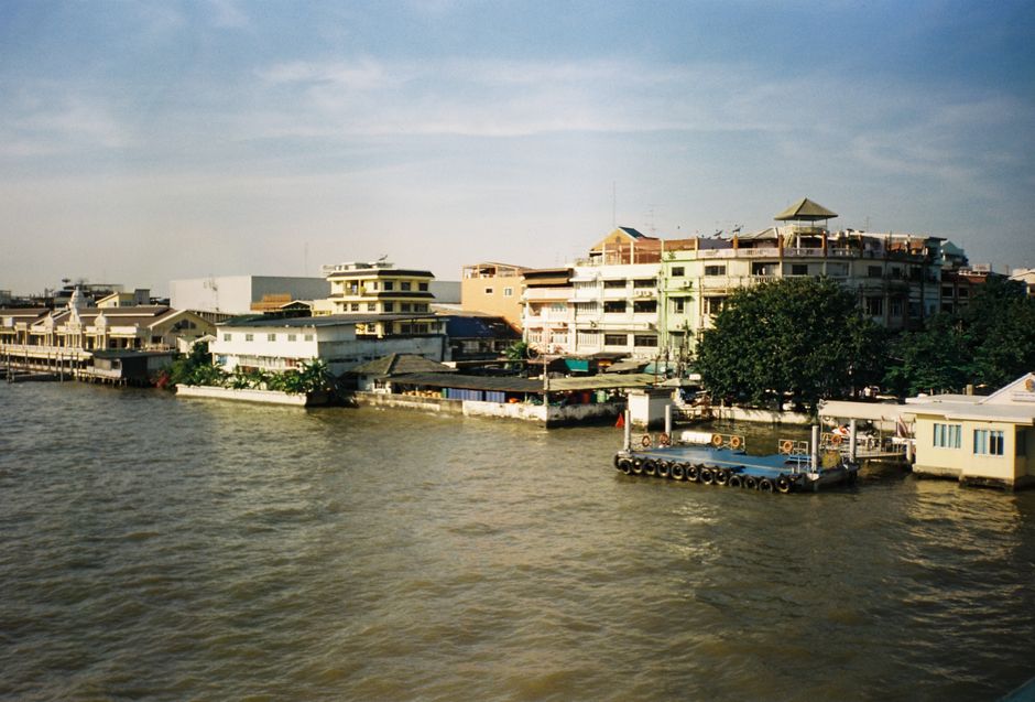 Charming riverside cityscape of Bangkok, showcasing urban buildings and waterfront ambiance under a clear sky.
