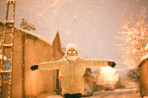 Free A child dressed warmly, enjoying a snowy winter night on city streets. Stock Photo