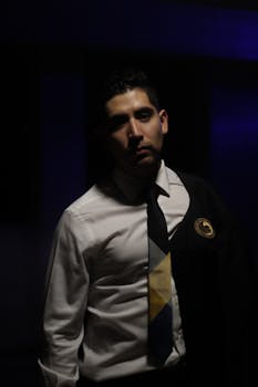 A moody portrait of a confident man in a white shirt and dark tie exuding elegance.