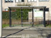 Street view of a modern empty bus stop shelter in a sunny urban residential area.