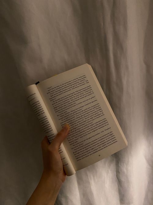Free An open book held by a hand against a soft, neutral background. Stock Photo