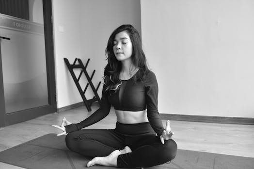 A woman practicing meditation in a yoga pose indoors, promoting relaxation and mindfulness.