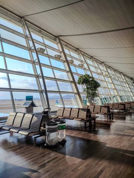 Spacious and empty airport seating area with large windows offering scenic runway views.