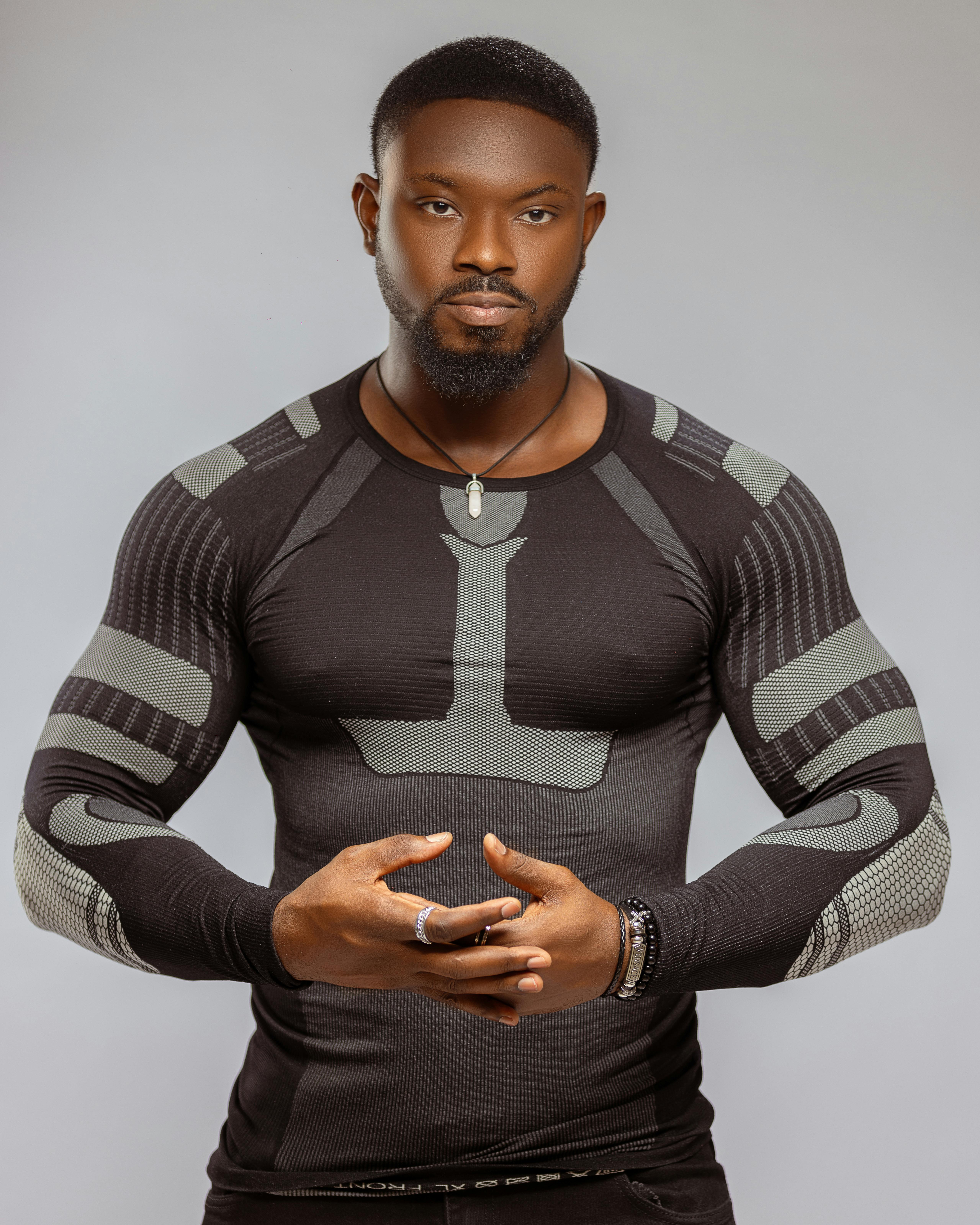 Portrait of a muscular man in sportswear on a gray background exhibiting confidence and style.