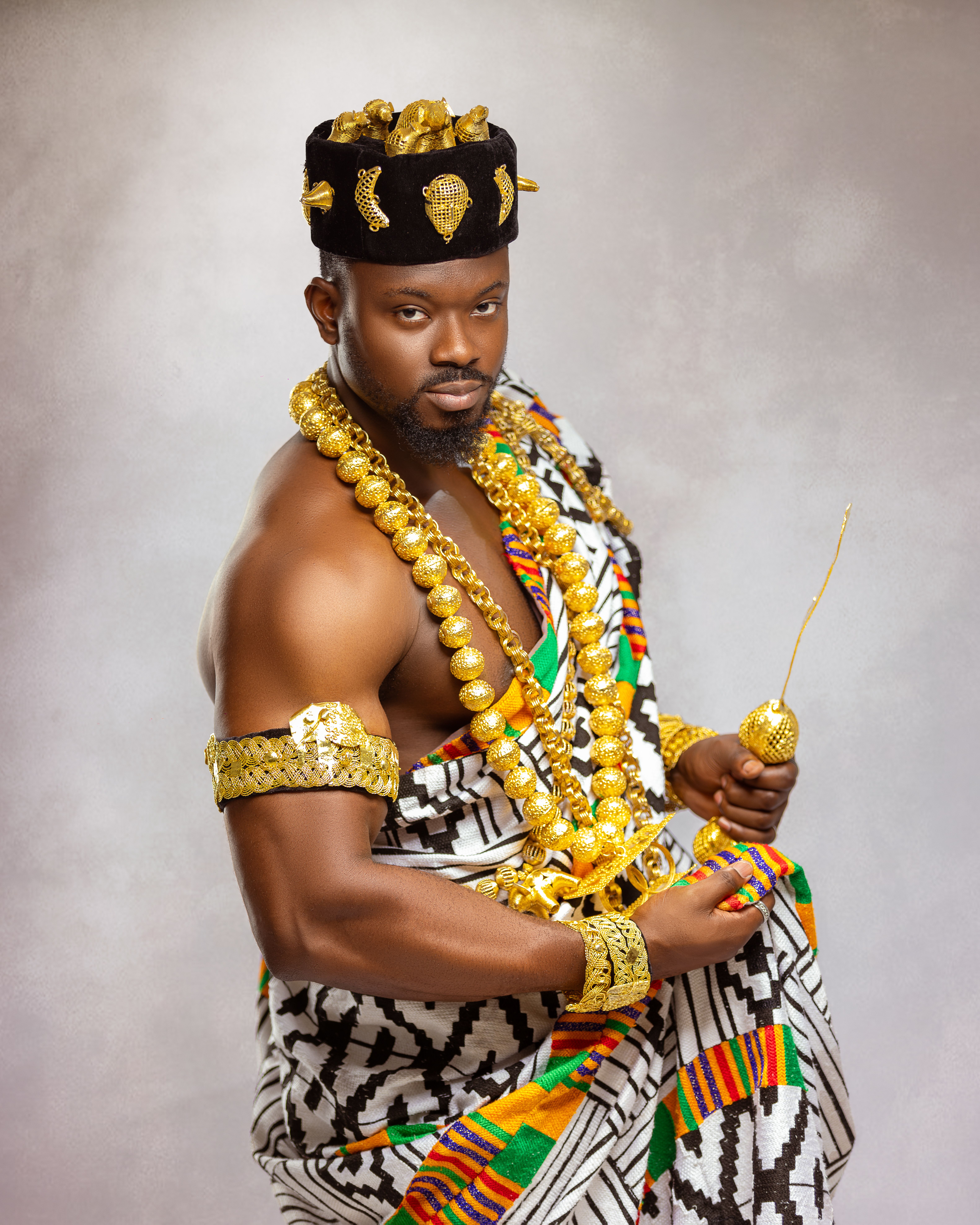 Elegant portrait showcasing African tribal attire and gold jewelry in a studio setting.