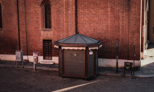 Free Historic octagonal booth against a rustic red brick building on a deserted European street corner. Stock Photo