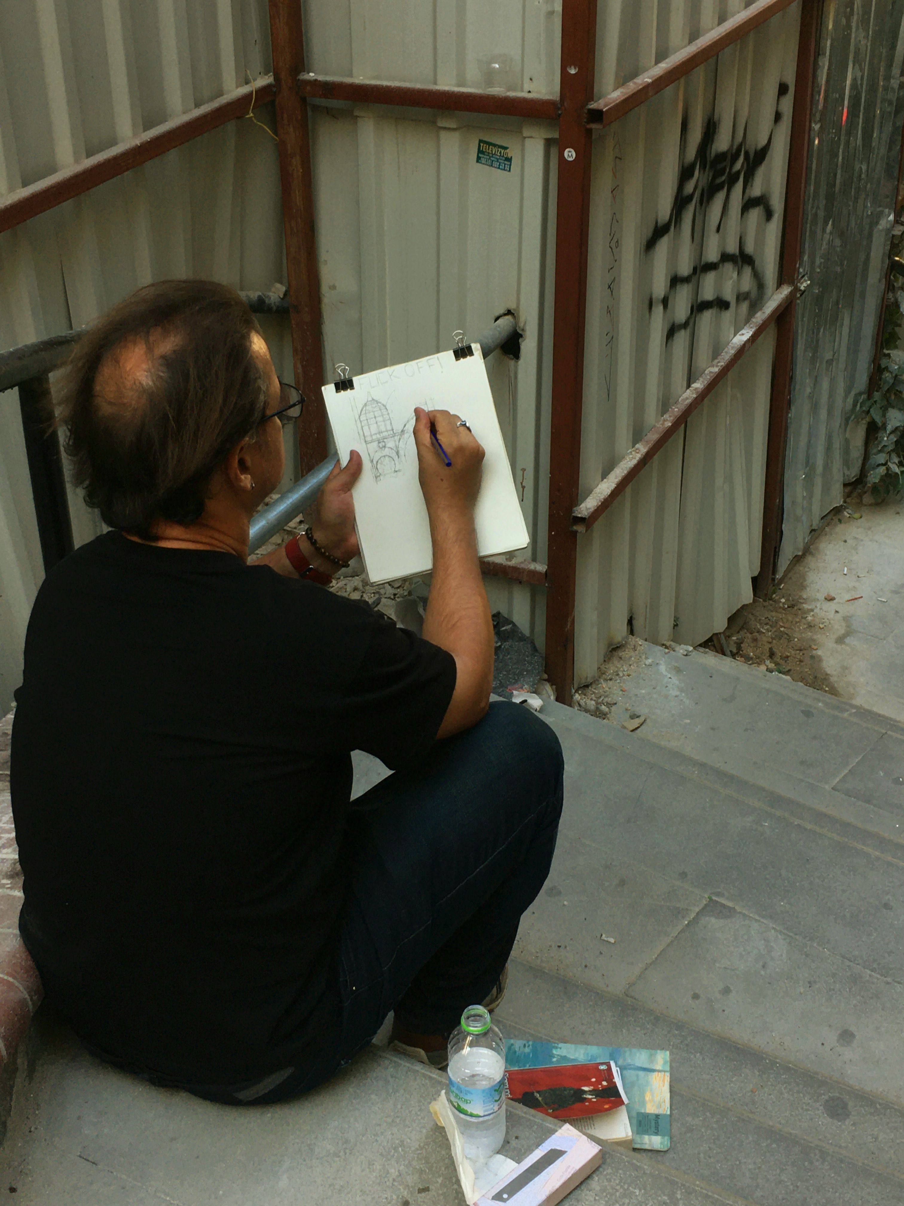 A street artist in Istanbul captures urban life through sketches on stairs. Back view, artistic scene.