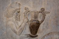 Detailed ancient Persian relief sculpture depicting a man holding a decorative jug.