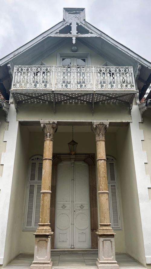 Free Antique building facade with ornate columns and intricate balcony work. Stock Photo