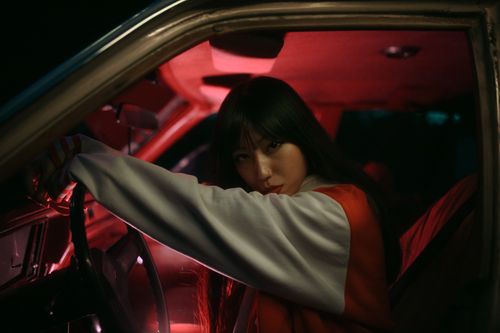 Free Portrait of a woman sitting in a car with striking red lighting at night. Stock Photo