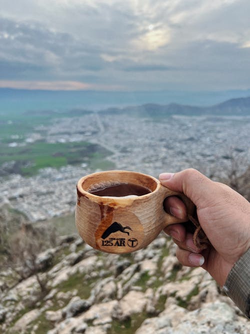 Close-up of a Man Holding a Cup of Tea on the Background of Mountains 