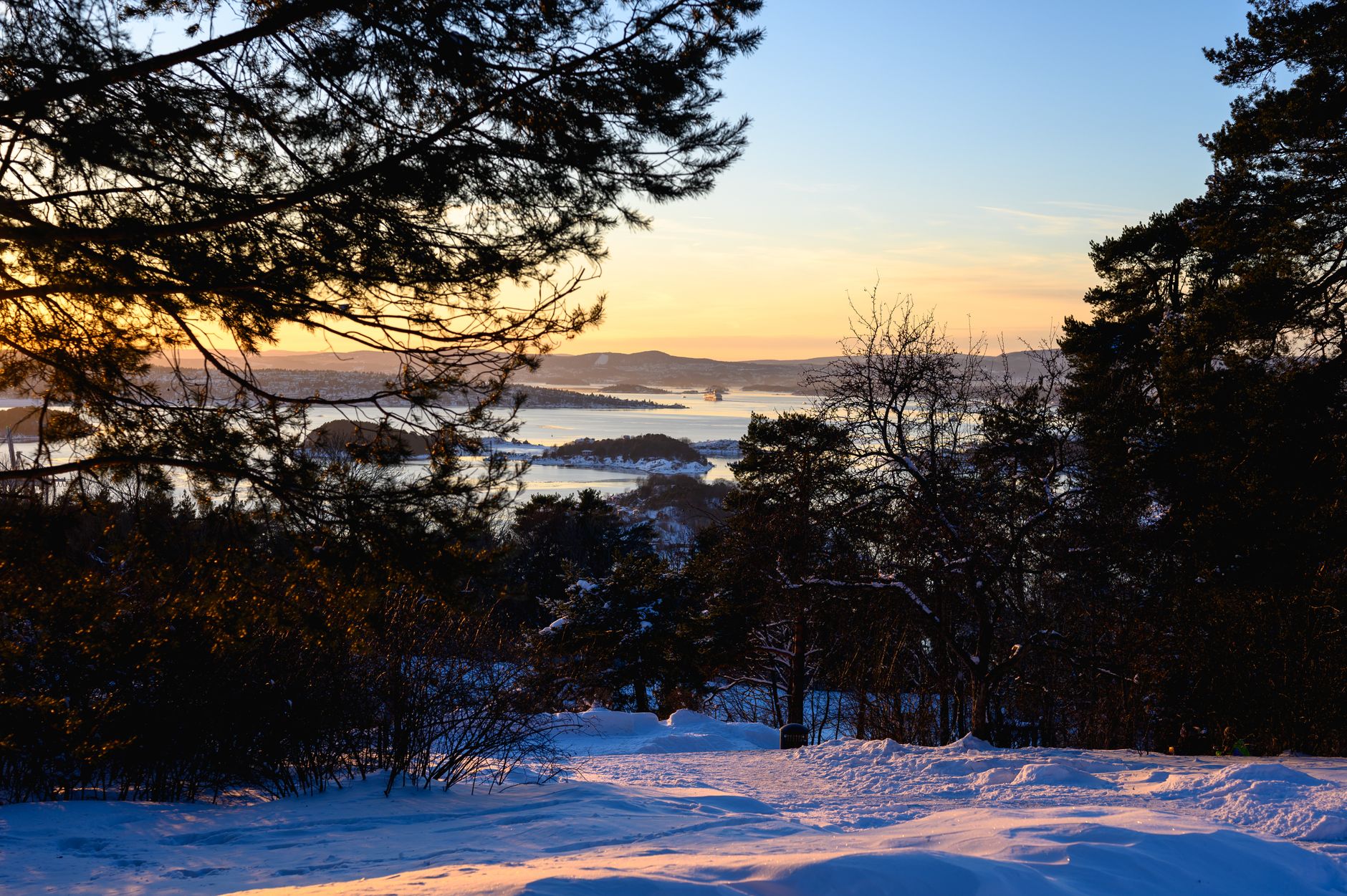 Captivating winter sunset overlooking the snowy landscape and forests near Oslo, Norway.
