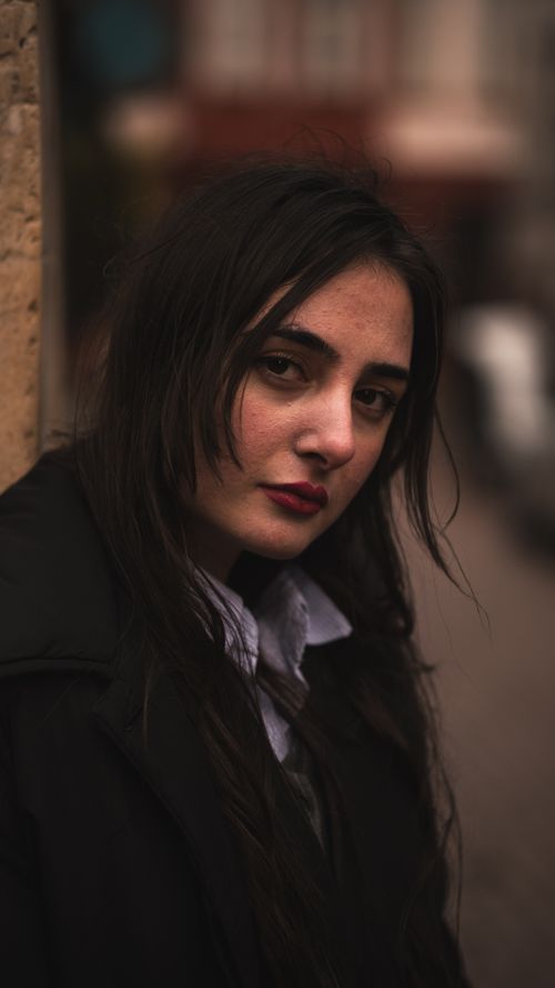 Free Emotional portrait of a woman with long hair against a textured wall in an urban setting. Stock Photo