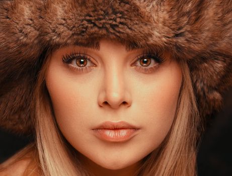 Elegant close-up portrait of woman wearing fur hat, showcasing natural beauty.