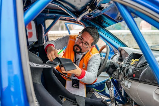 A racing car inspector with eyeglasses checks interior components and safety features in a blue race car.