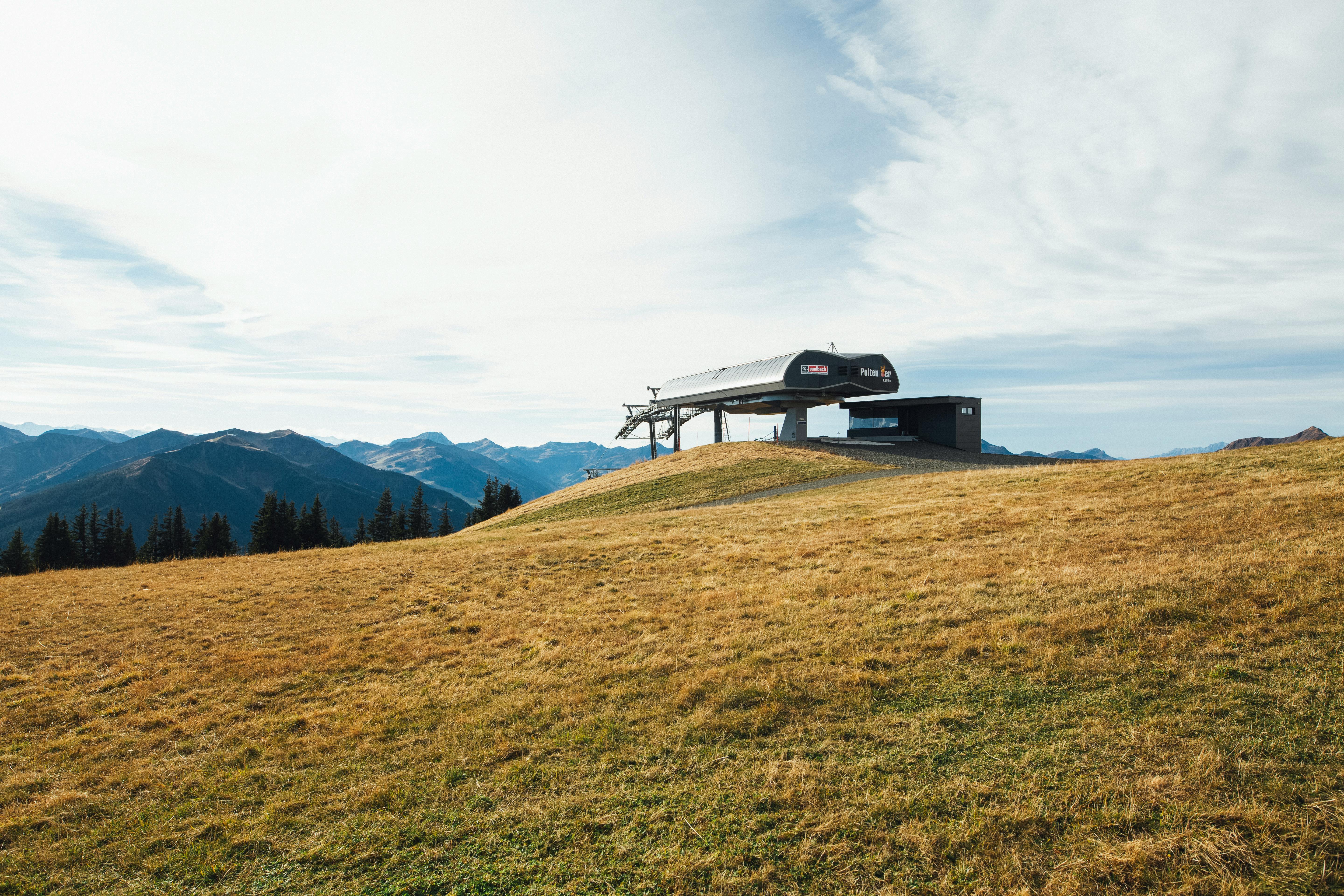 Prescription Goggle Inserts - Ski lift station on a grassy slope with a stunning mountain backdrop under cloudy skies.