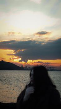 A peaceful silhouette against a vibrant sunset by the industrial harbor.