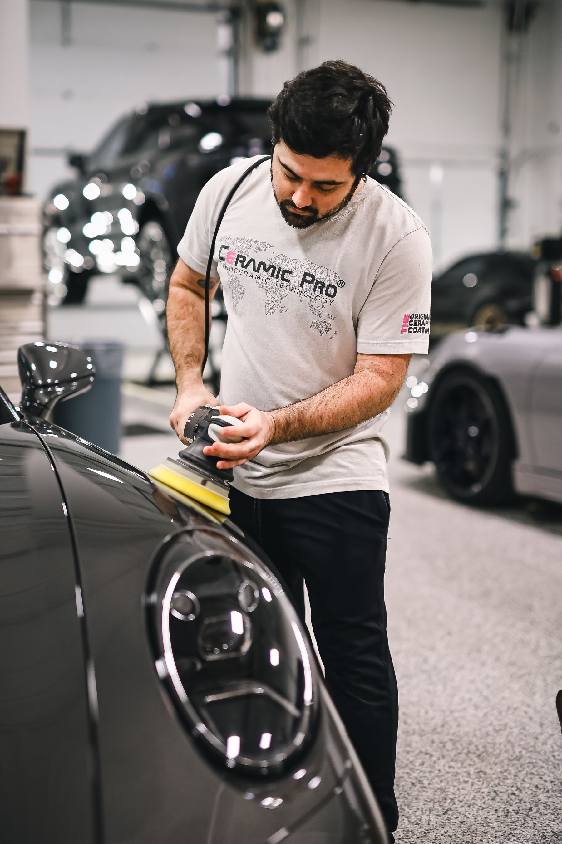 Technician polishing a sports car in a detailing studio