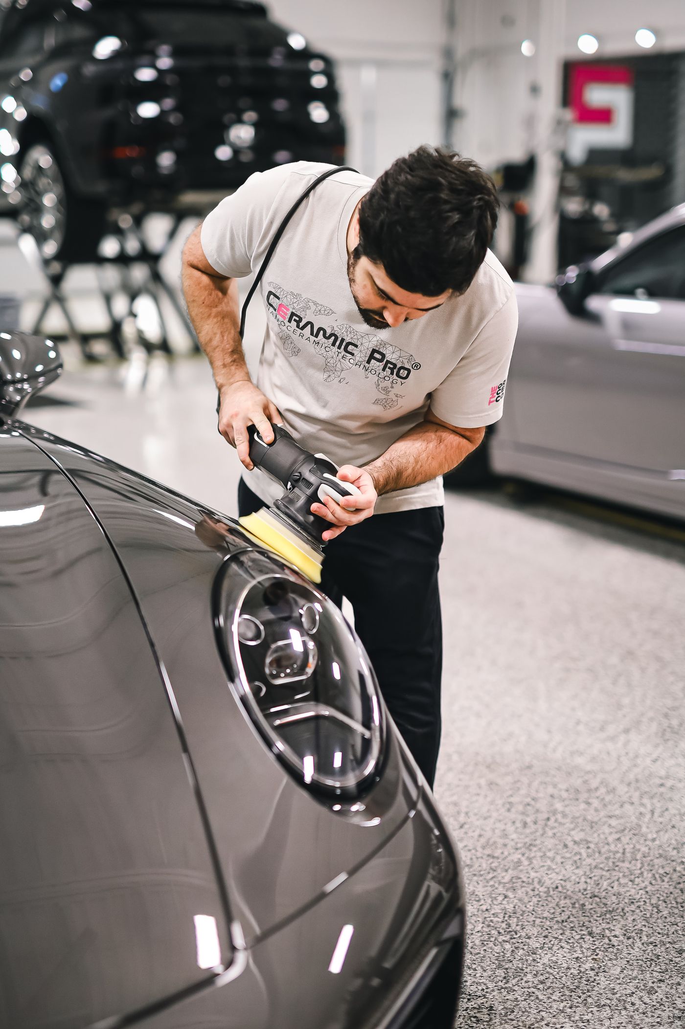 Detailer polishing the front of a luxury car
