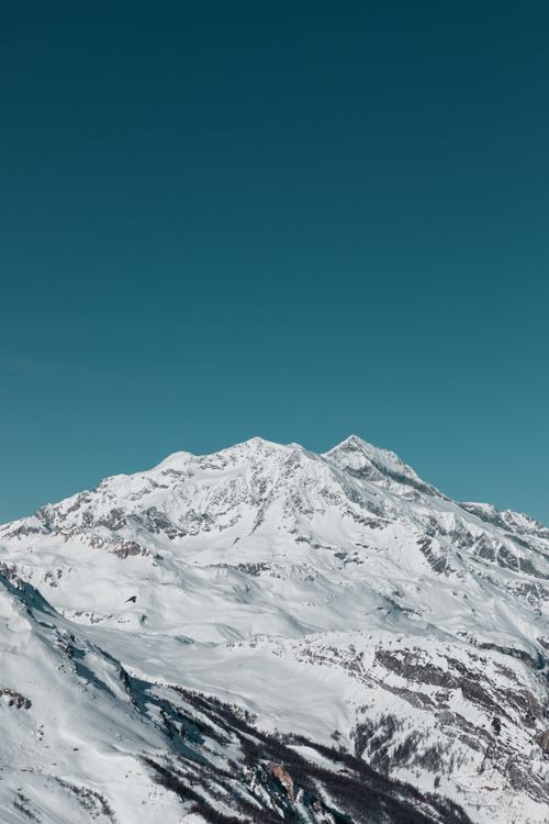 Free A breathtaking view of snow-covered mountains under a clear blue sky in Val-d'Isère, France. Stock Photo