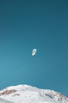 Thrilling paragliding adventure above snow-covered mountains in Val-d'Isère, France, showcasing winter sports and scenic landscapes.