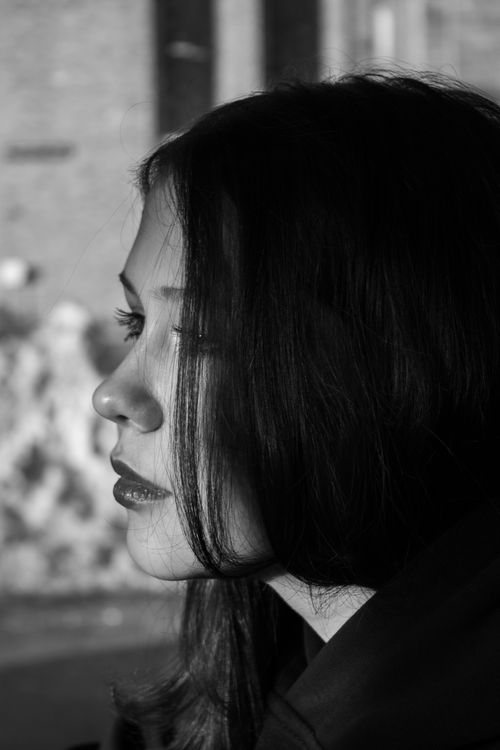 Free Elegant black and white profile portrait of a young woman with sunlight highlighting her features. Stock Photo