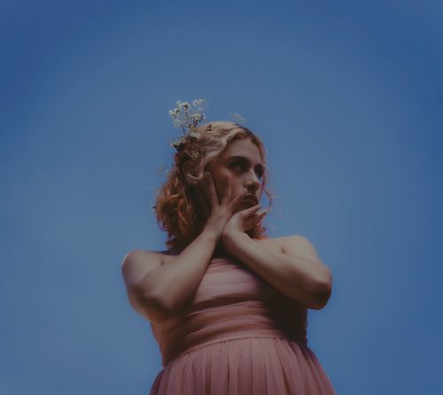 Free Fashion portrait of a woman in a pink dress against a vibrant clear sky, featuring a floral headpiece. Stock Photo