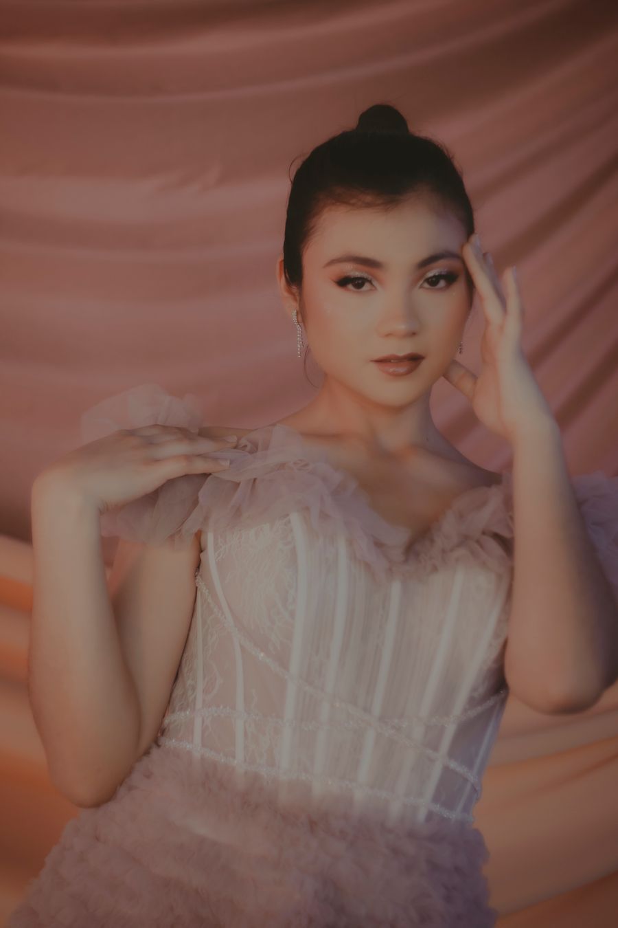 Portrait of a woman against draped blush fabric — photo by Ricardo E. Diaz Vega on Pexels