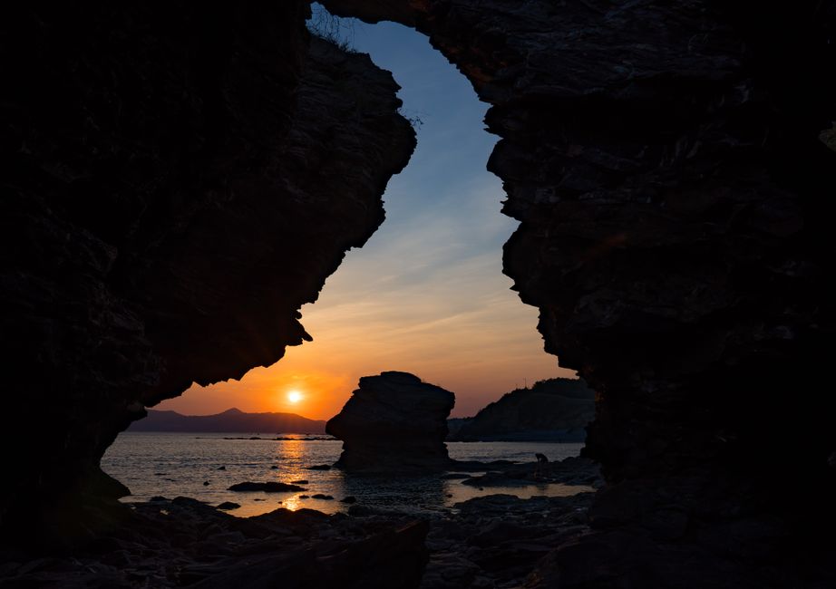 Captivating sunset view framed by rocky cliffs along Dalian's coast.