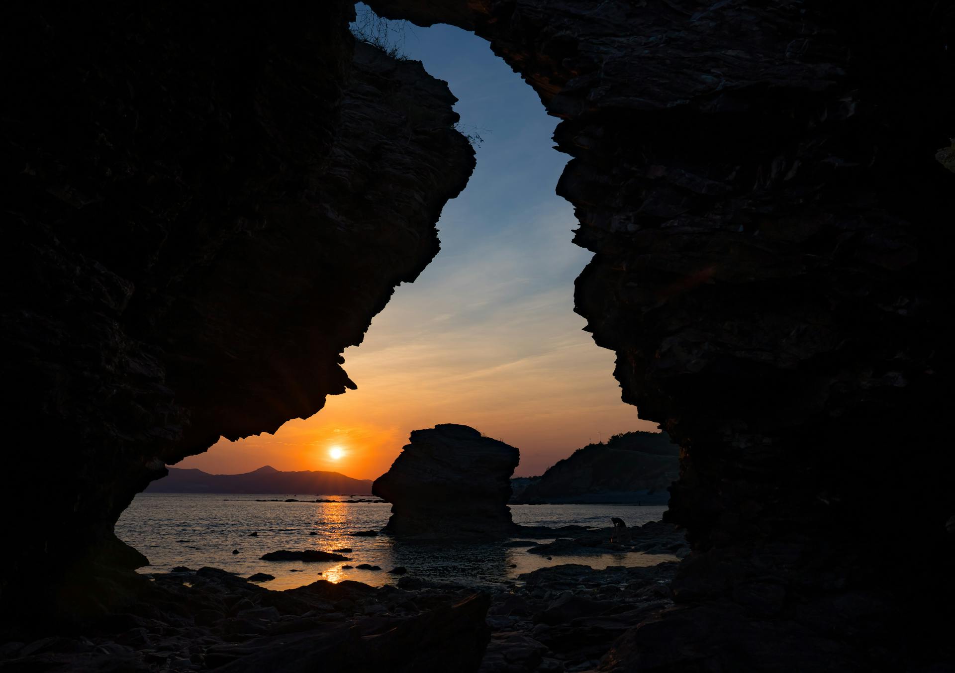 Captivating sunset view framed by rocky cliffs along Dalian's coast.