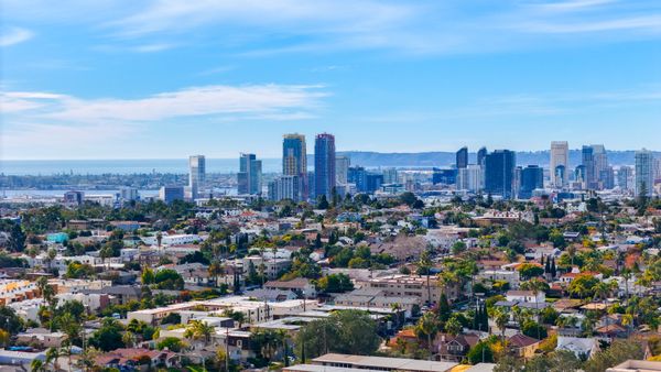 Aerial view of San Diego neighborhoods with the downtown skyline and bay behind them, for readers weighing Los Angeles vs. San Diego
