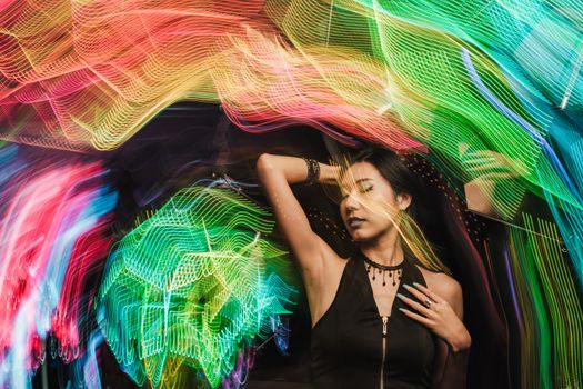 Artistic fashion portrait of a woman with vibrant light trails creating a dynamic background.