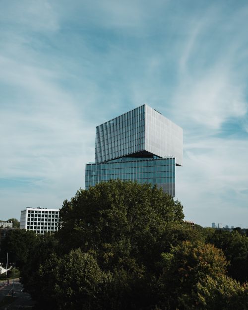 Free Contemporary architecture surrounded by lush greenery under a clear blue sky in an urban environment. Stock Photo