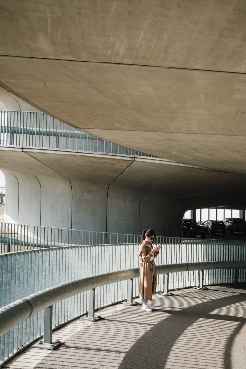 Free Modern urban architecture featuring a woman standing under a concrete structure. Stock Photo