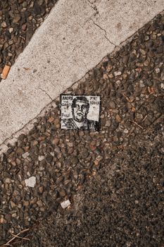 Close-up view of a sticker on a textured gravel street highlighting urban street art.