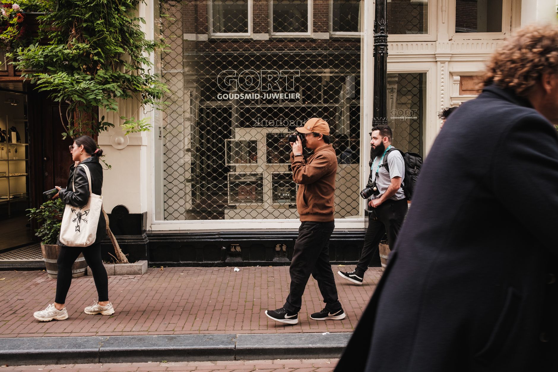 An Amsterdam canal street with people walking past fashion shops