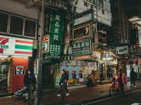 Busy Hong Kong street scene with neon signs and pedestrians at night, showcasing urban life.