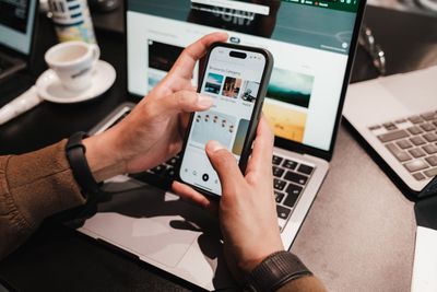 Mani con smartphone sopra un portatile