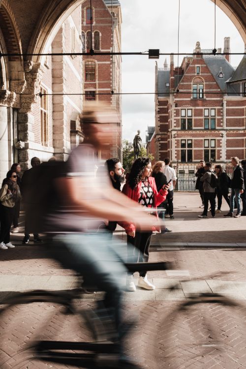 Free Motion blur of a cyclist passing iconic Dutch architecture in an urban setting. Stock Photo