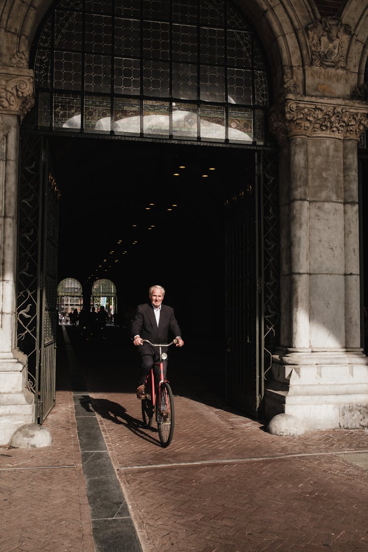 Elderly Man In Suit Riding Bike In Amsterdam