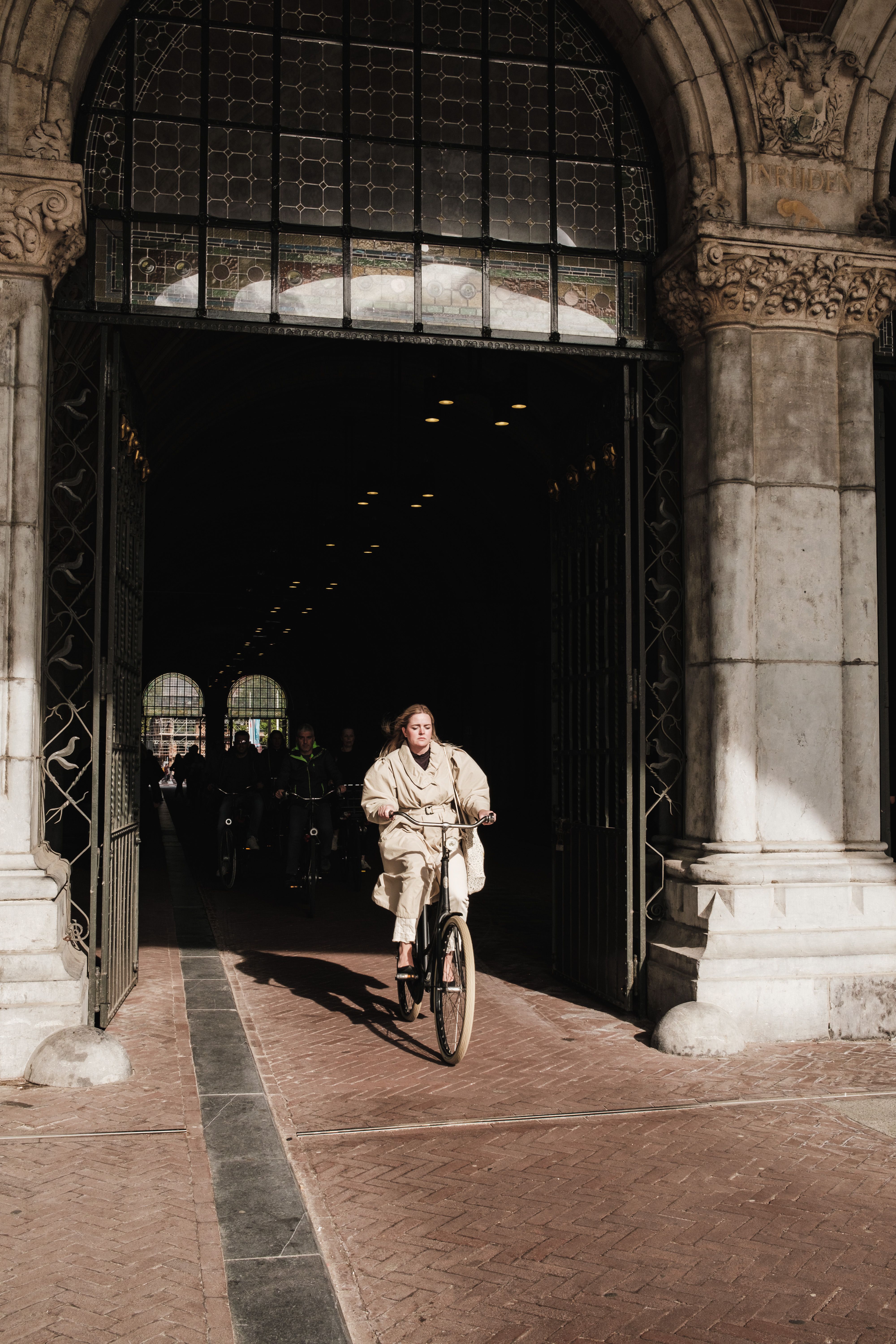 A woman rides a bicycle through a historic tunnel in Amsterdam, capturing urban life