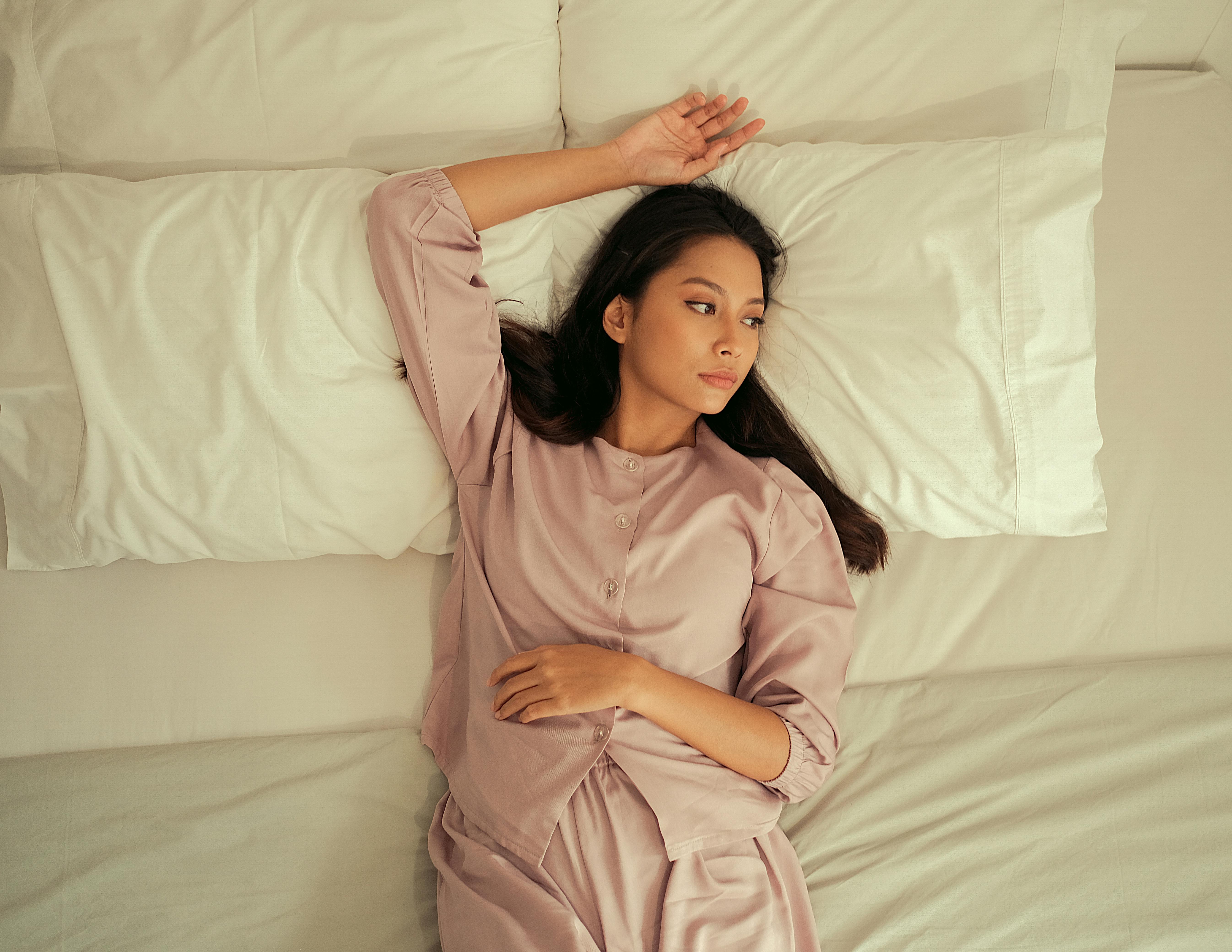 Woman relaxing on a bed in comfortable pajamas, enjoying leisure time indoors.