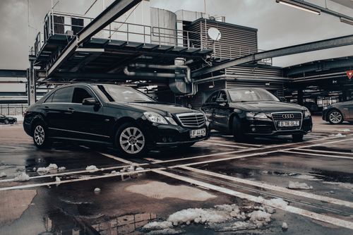 Free Two black luxury cars parked in a winter industrial setting showcasing elegance and modern design. Stock Photo