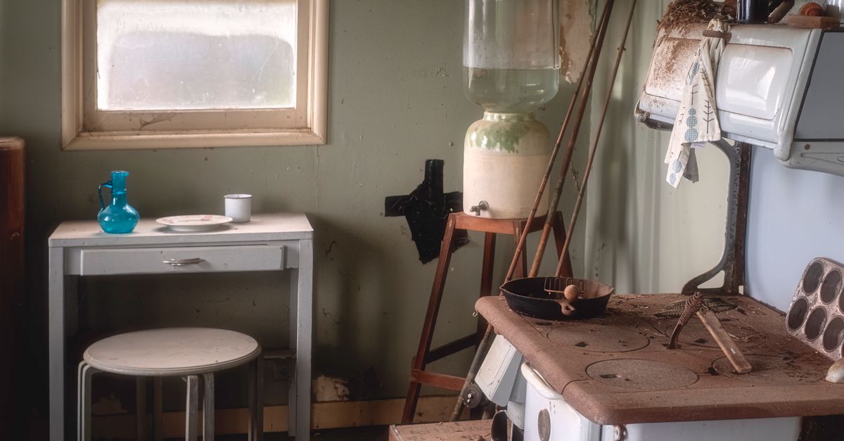 Charmoso interior de cozinha vintage com um fogão antigo, jarro de água e elementos de decoração rústica.