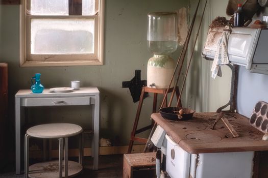Charming vintage kitchen interior featuring an old stove, water jug, and rustic decor elements.