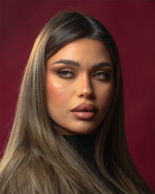 Free Close-up portrait of a glamorous woman with professional makeup on a rich red background. Stock Photo