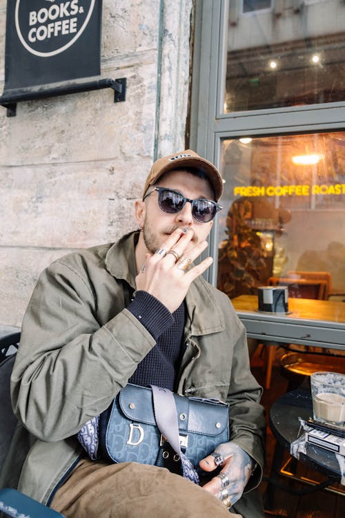 A man smoking a cigarette outside of a coffee shop