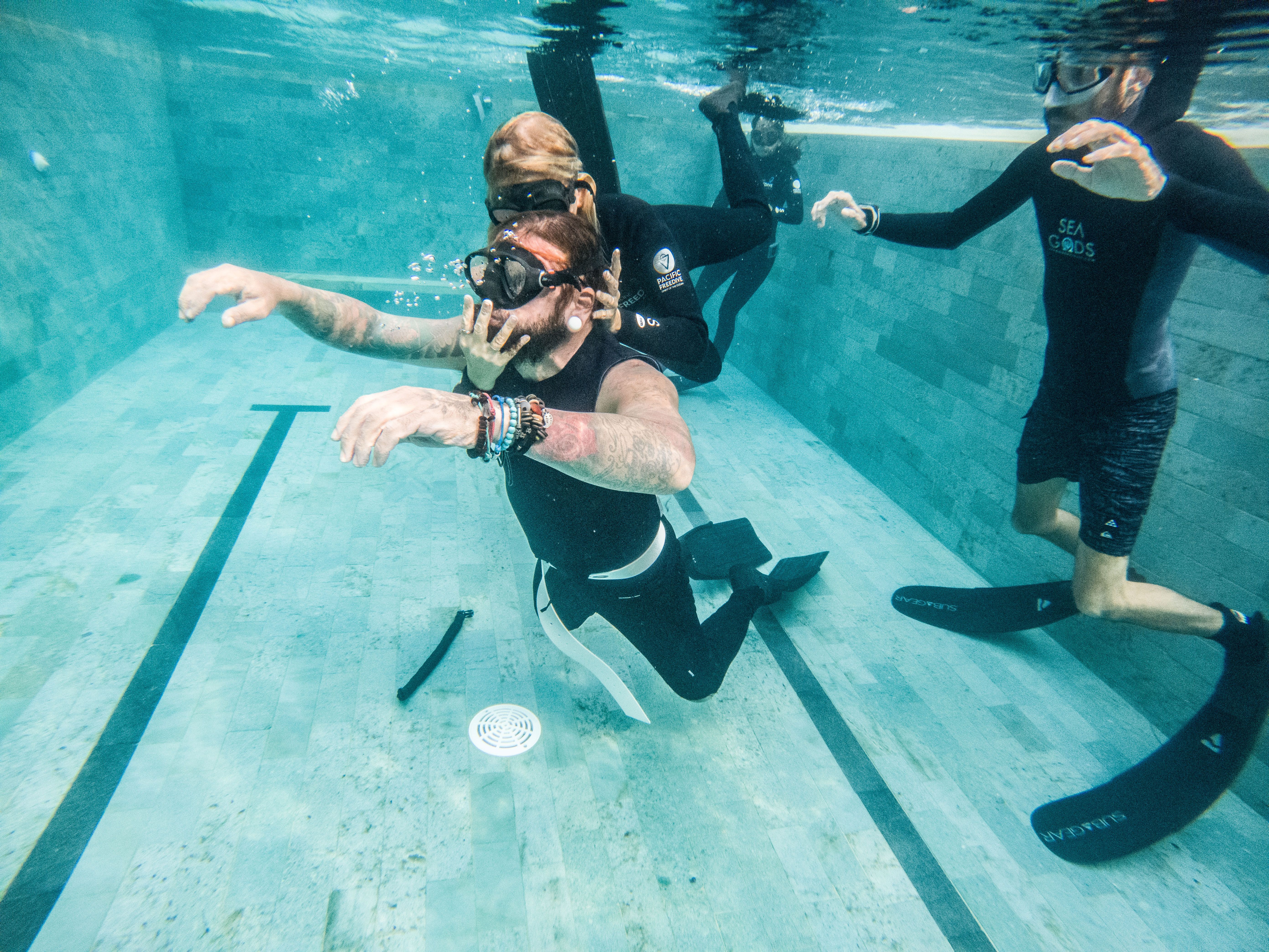 Group practicing freediving techniques underwater in a swimming pool