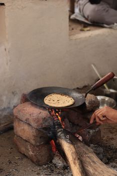Rustic outdoor bread cooking on open fire with handmade tools.